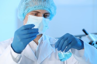 Photo of Scientist dripping sample into flask in laboratory. Medical research