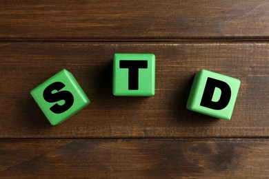 Photo of Abbreviation STD made with cubes on wooden table, flat lay