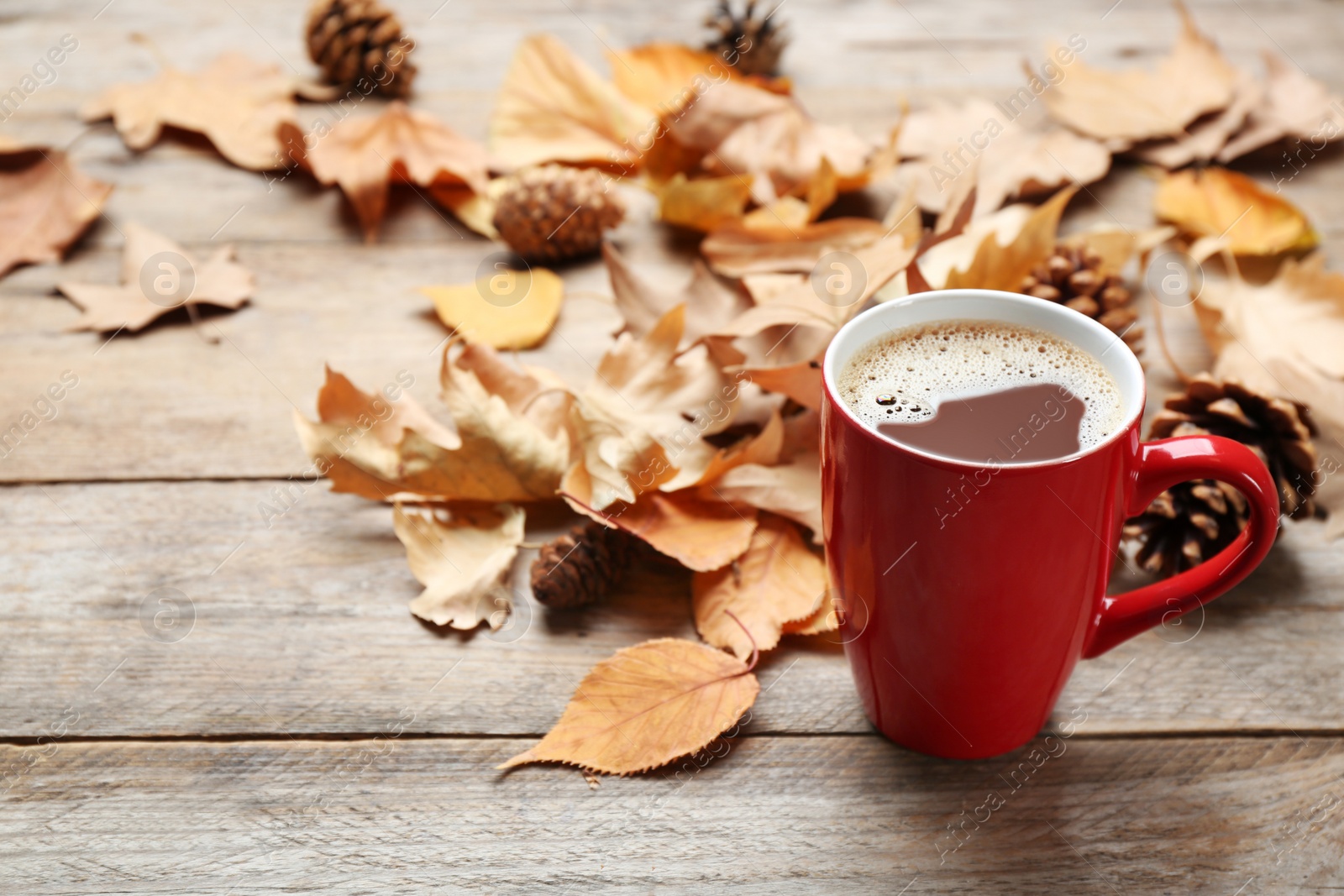 Photo of Cup of hot drink and leaves on wooden table. Cozy autumn atmosphere