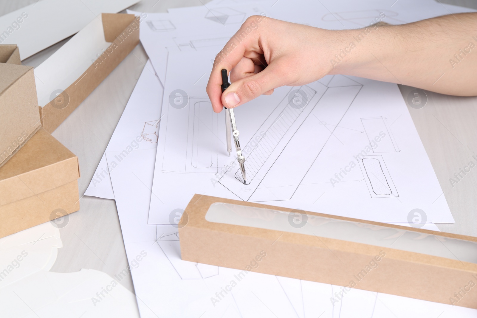 Photo of Man creating packaging design at light wooden table, closeup