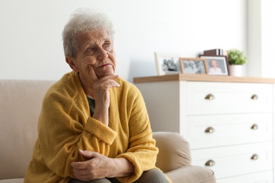Thoughtful elderly woman on sofa at home