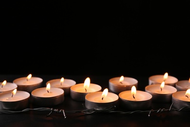 Photo of Burning candles and barbed wire on black background, space for text. Holocaust memory day