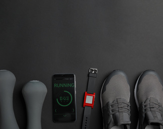 Flat lay composition with fitness equipment and smartphone on black background. Space for text