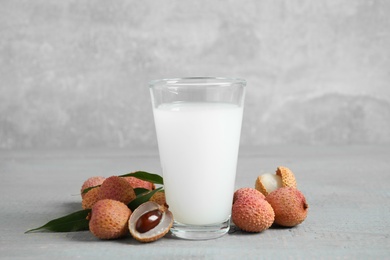 Photo of Fresh lychee juice and fruits on grey wooden table