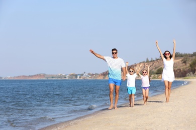 Photo of Happy family walking on sandy beach near sea. Summer holidays