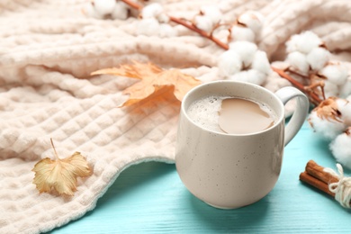 Photo of Composition with coffee and warm plaid on turquoise wooden table