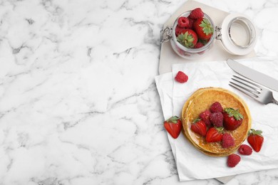 Tasty pancakes served with honey and berries on white marble table, flat lay. Space for text