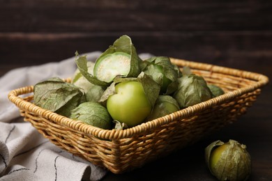 Fresh green tomatillos with husk in wicker basket on table, closeup