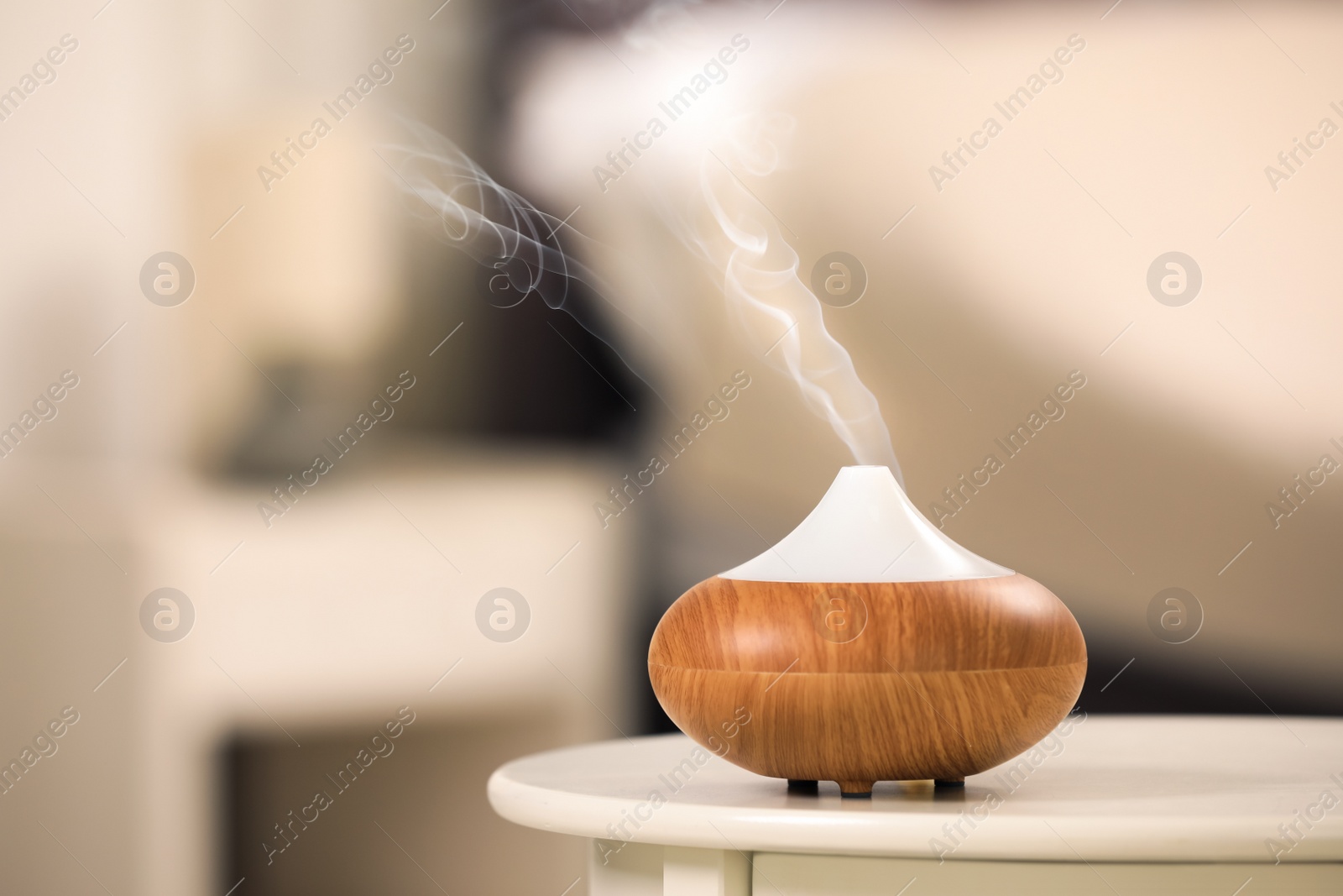 Photo of Modern essential oil diffuser on table indoors. Space for text