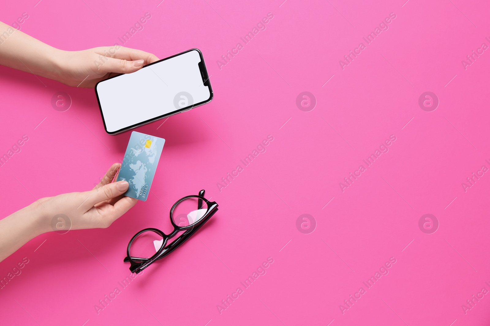 Photo of Online payment. Woman with smartphone, credit card and glasses on pink background, top view. Space for text