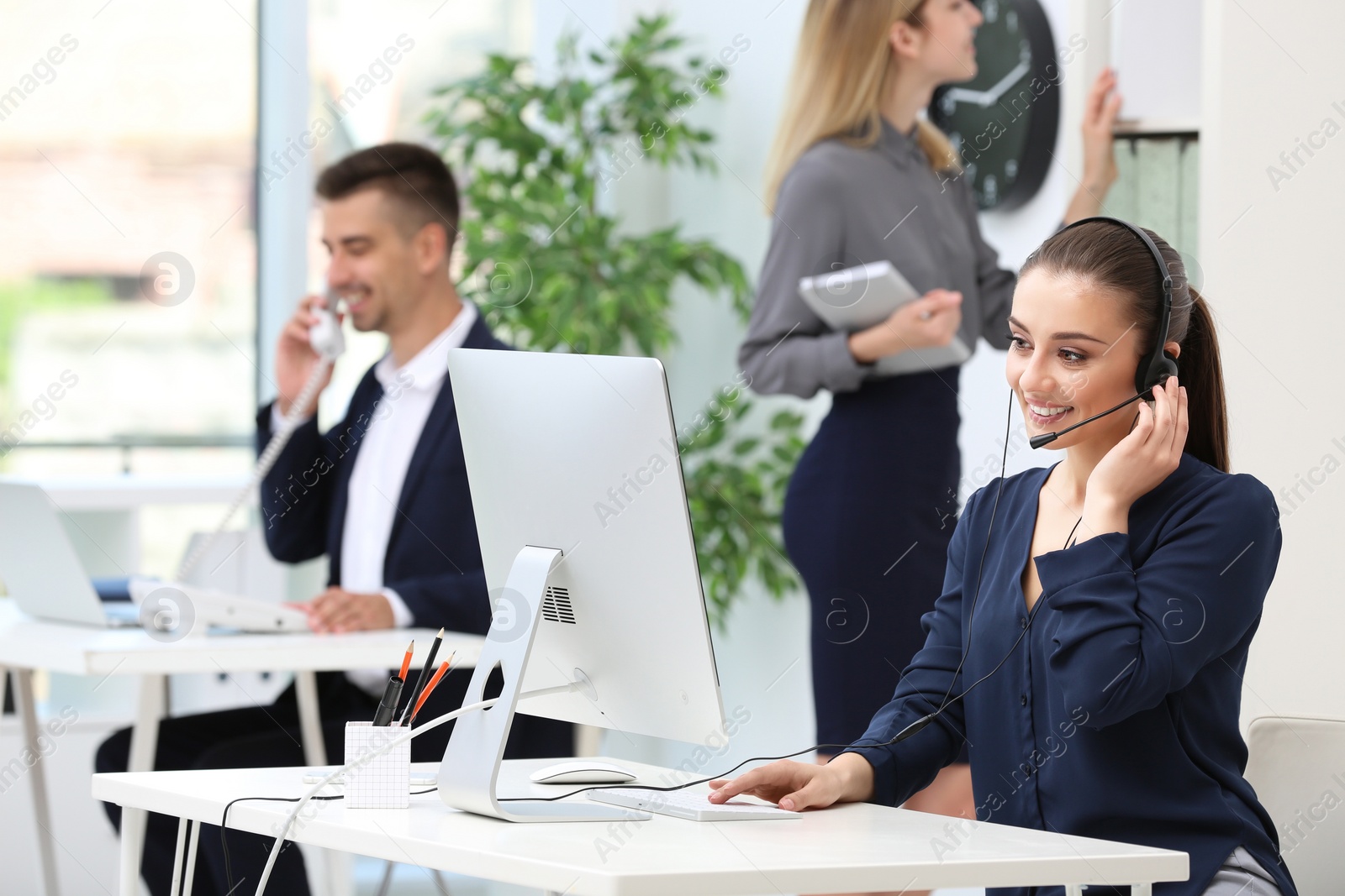 Photo of Female receptionist with headset at desk in office