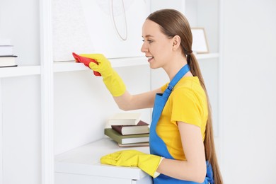 Photo of Woman cleaning shelf with rag at home