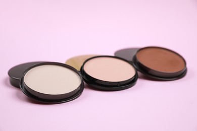 Different face powders on pink background. Decorative cosmetic