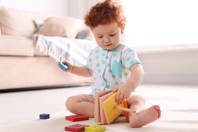 Cute little child playing with toy on floor at home