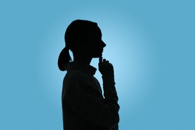 Silhouette of anonymous woman on light blue background