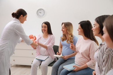 Group of pregnant women with doctor at courses for expectant mothers indoors