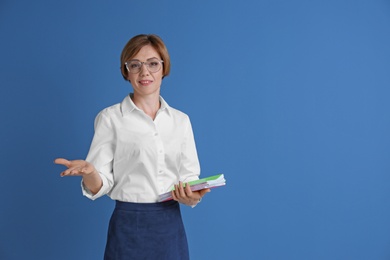 Photo of Portrait of female teacher with notebooks on color background