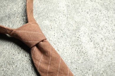One striped necktie on grey textured background, closeup. Space for text