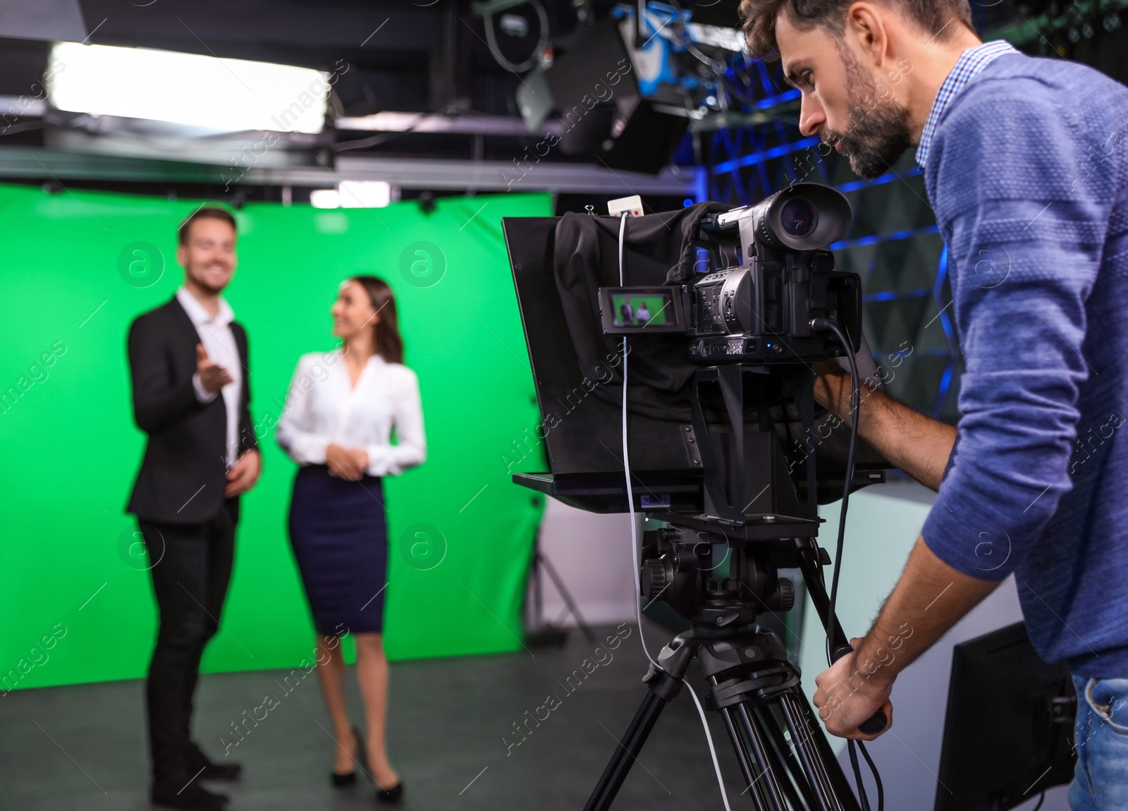 Photo of Presenters and video camera operator working in studio. News broadcasting