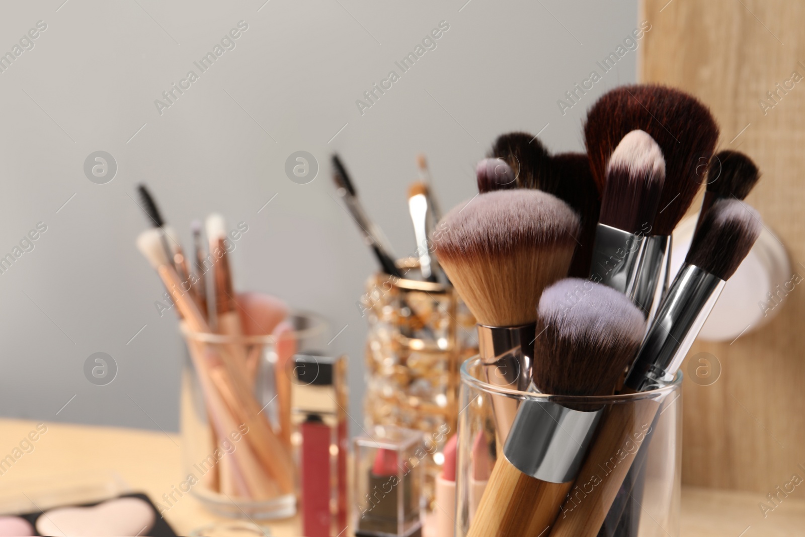 Photo of Set of professional brushes and makeup products near mirror, closeup. Space for text