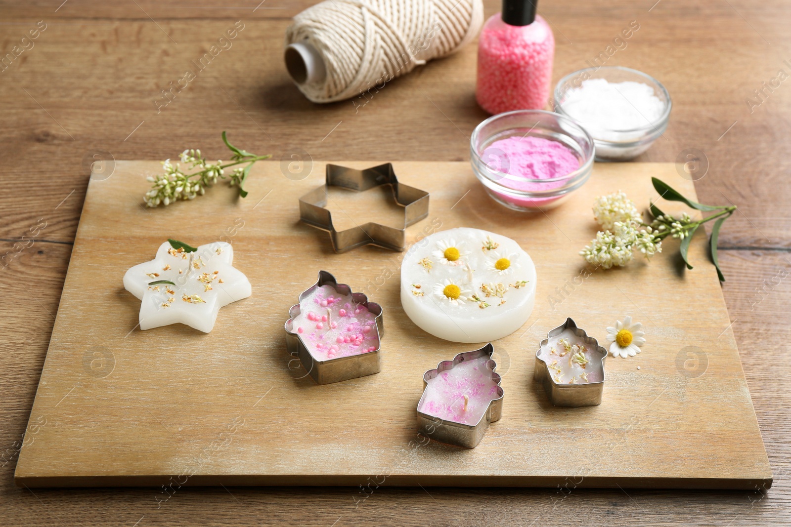 Photo of Different handmade candles and cutters on wooden background