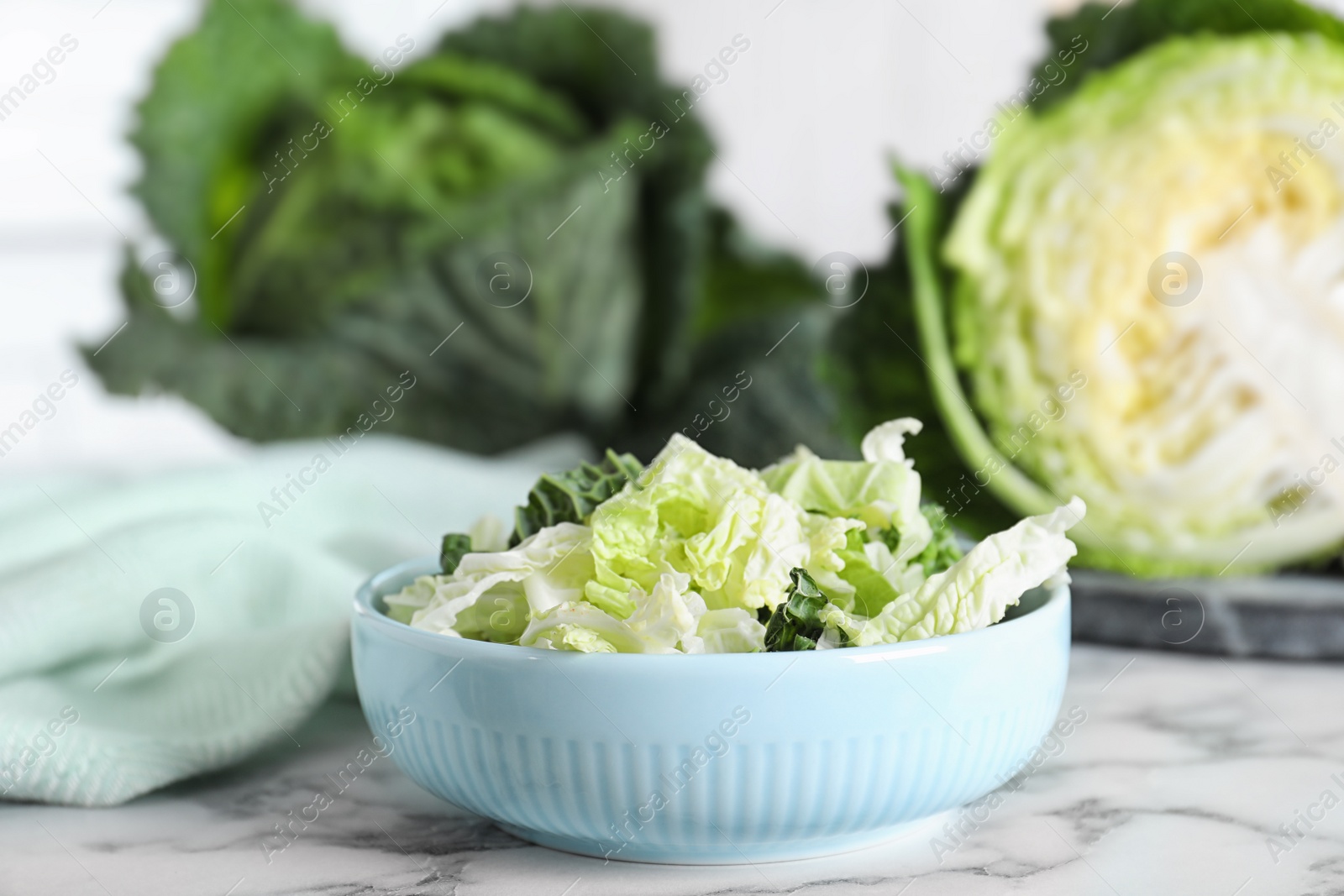 Photo of Chopped fresh green savoy cabbage in bowl on white marble table