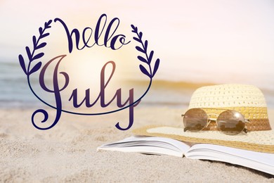 Image of Hello July. Open book, sunglasses and hat on sandy beach near sea