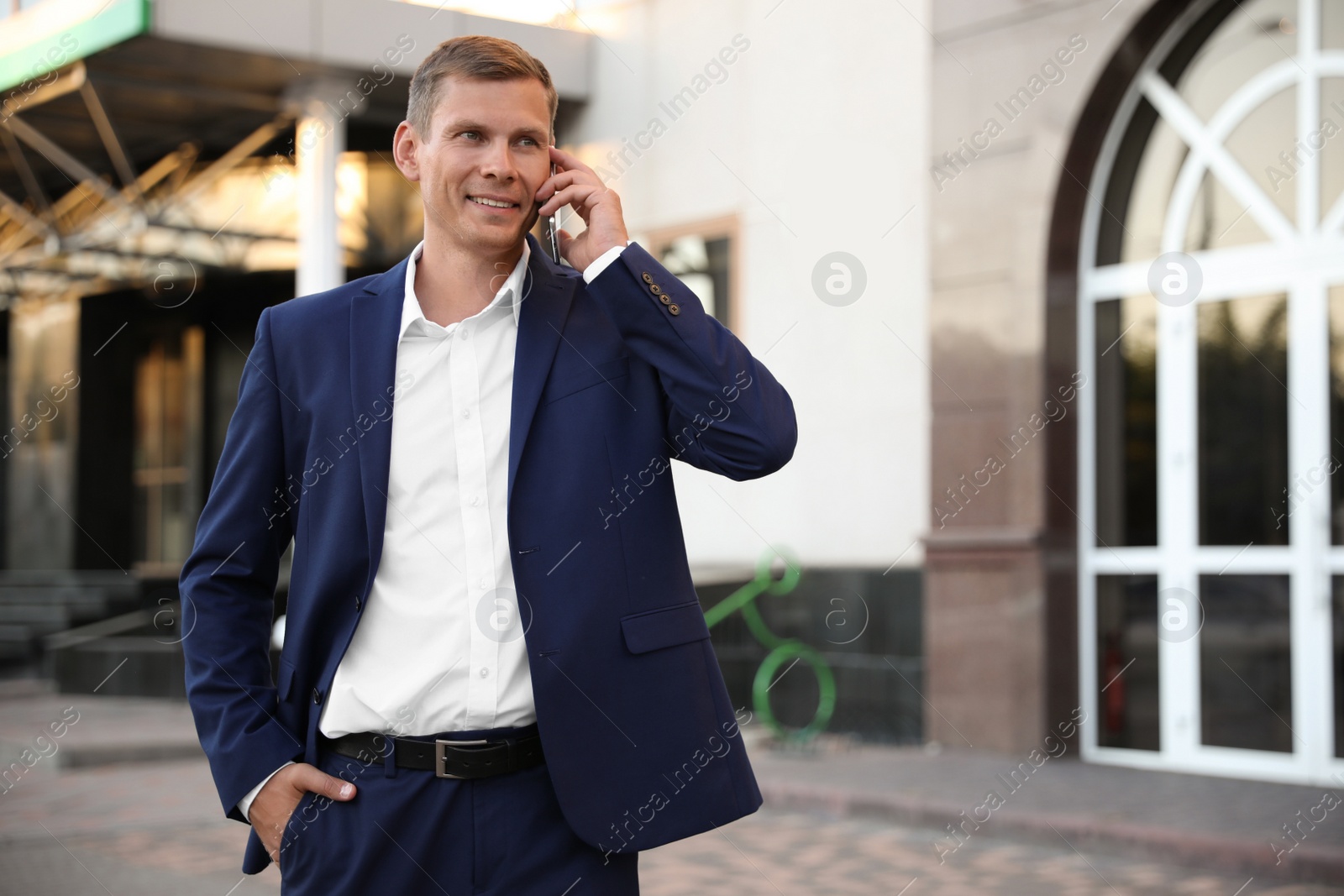 Photo of Businessman talking on phone near modern building