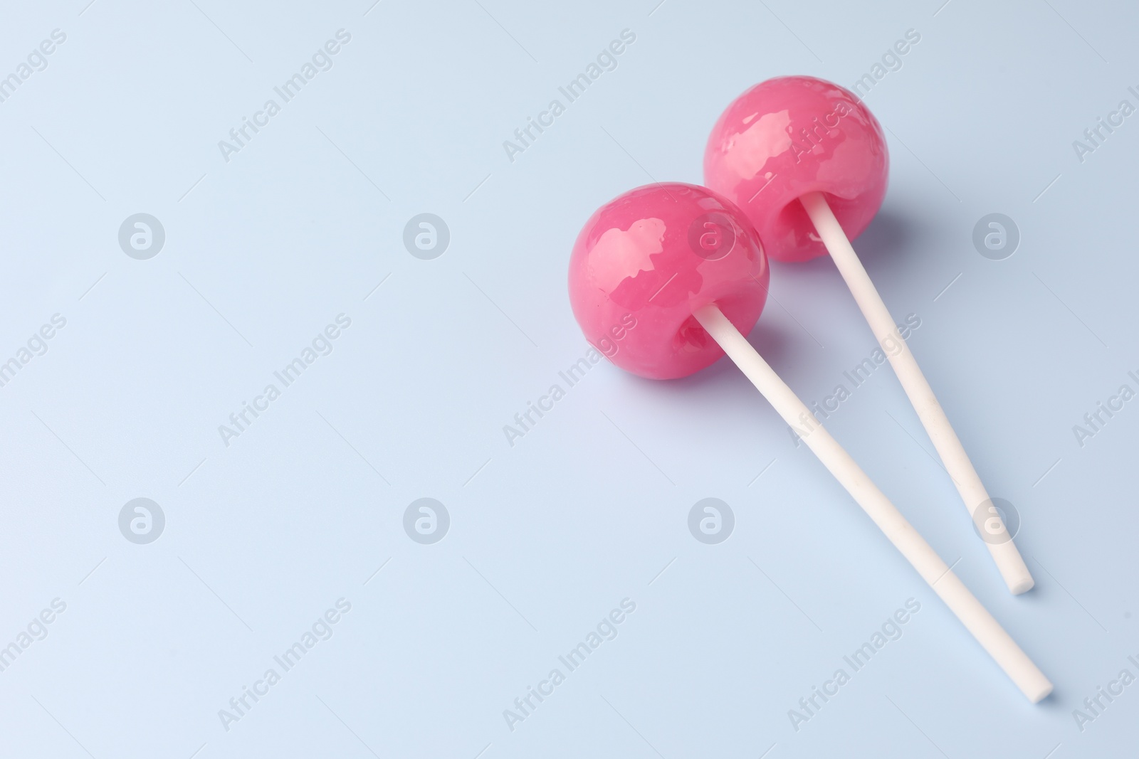 Photo of Two tasty lollipops on light blue background. Space for text