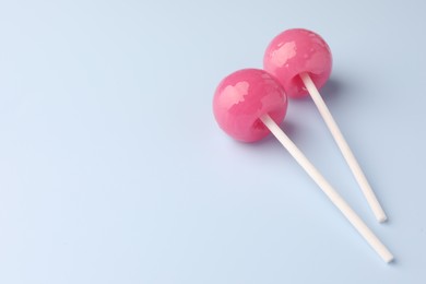 Photo of Two tasty lollipops on light blue background. Space for text