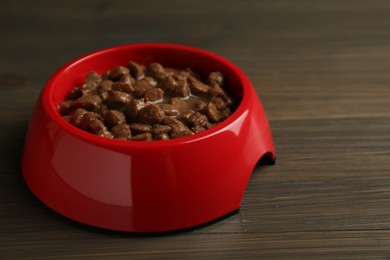 Photo of Wet pet food in feeding bowl on wooden background
