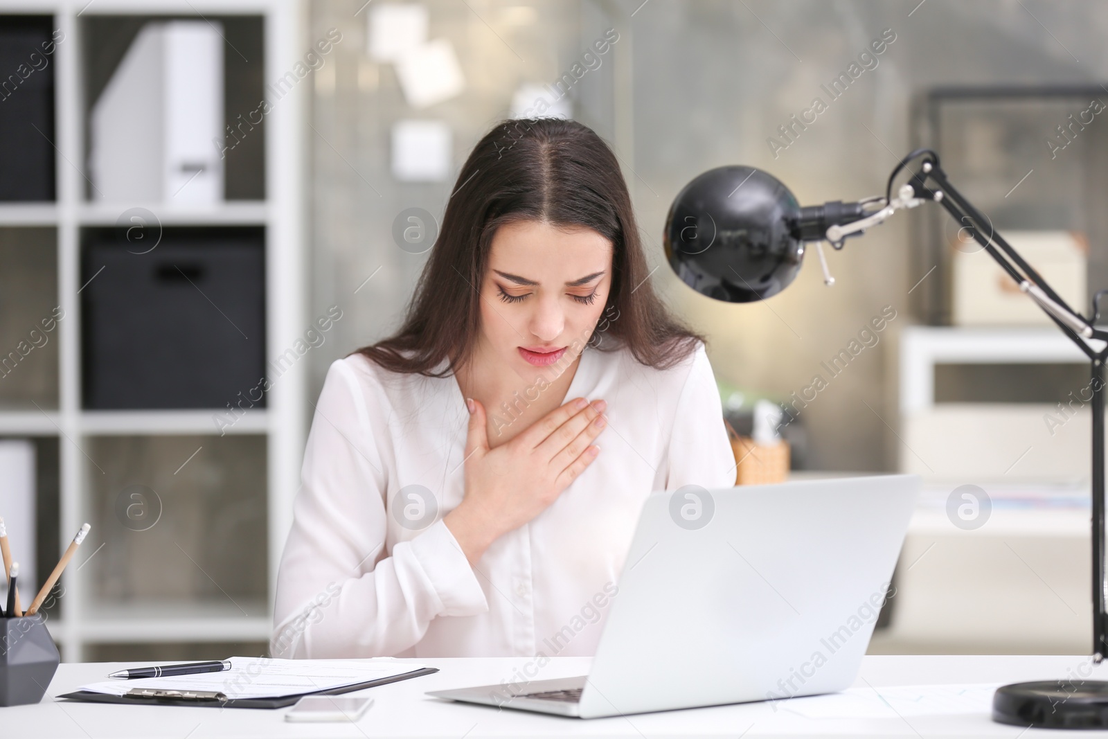 Photo of Young woman suffering from chest pain in office