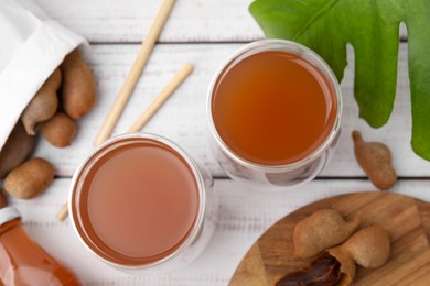 Photo of Tamarind juice and fresh fruits on white wooden table, flat lay