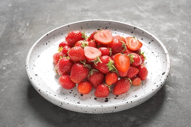 Photo of Plate with ripe strawberries on grey background