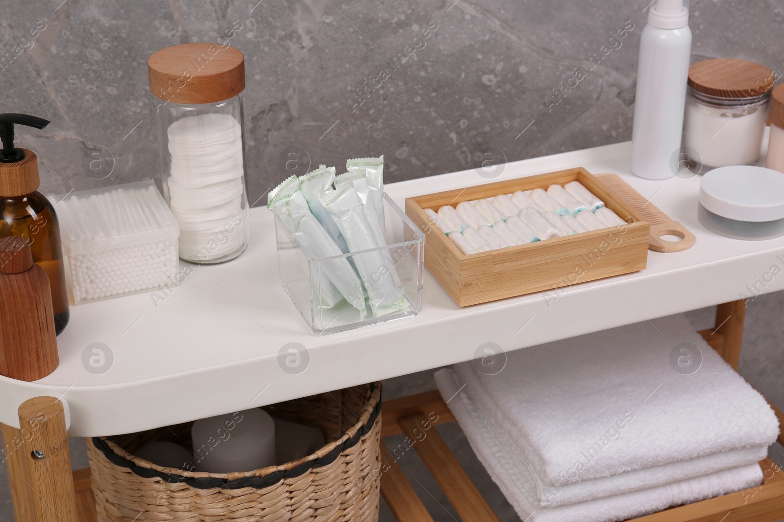 Photo of Many different tampons and personal care products on white table near grey wall