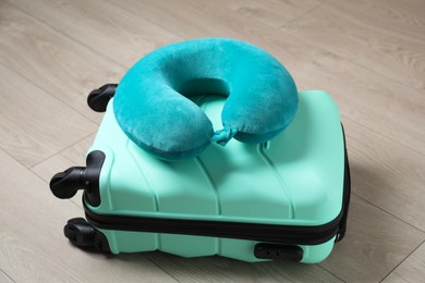 Photo of Turquoise travel pillow and suitcase on floor