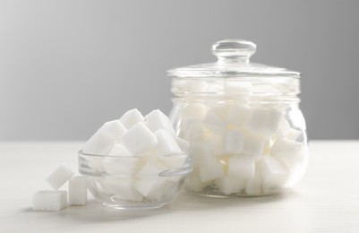 Photo of Glass jar and bowl with white sugar cubes on table