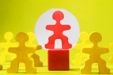 Photo of Wooden figures with red one on yellow background, closeup. Recruiter searching employee