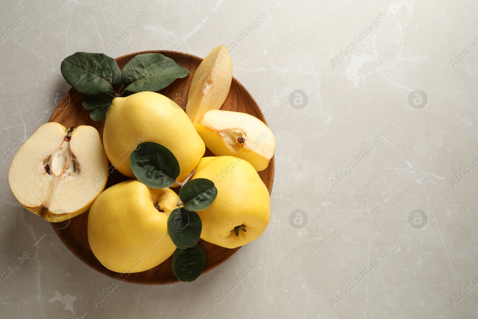 Photo of Fresh ripe organic quinces with leaves on light table, top view. Space for text