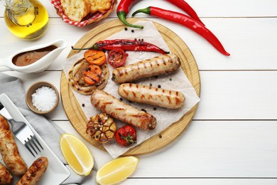 Photo of Tasty grilled sausages served on white wooden table, flat lay. Space for text