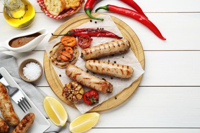 Tasty grilled sausages served on white wooden table, flat lay. Space for text