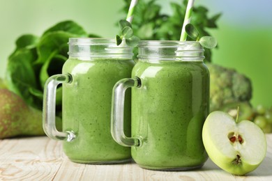 Photo of Mason jars of fresh green smoothie and ingredients on wooden table, closeup