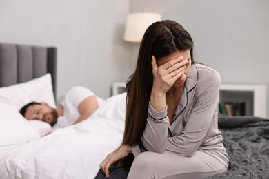 Photo of Stressed wife after quarrel with her husband sitting on bed, selective focus. Relationship problems