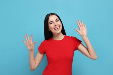 Photo of Happy woman giving high five with both hands on light blue background