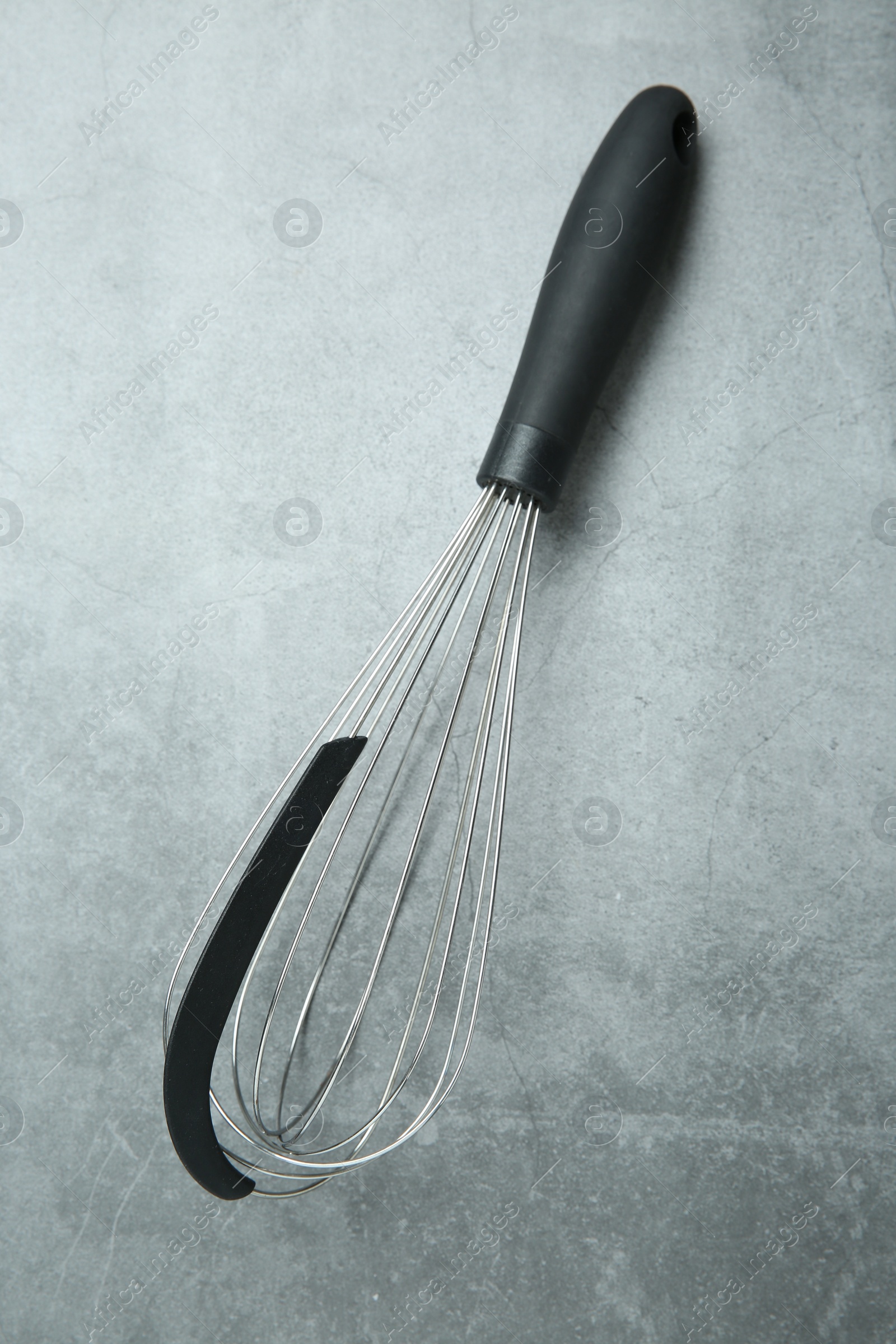 Photo of Metal whisk on gray table, top view