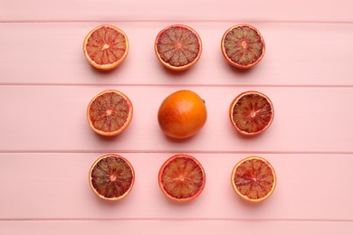 Photo of Many ripe sicilian oranges on pink wooden table, flat lay