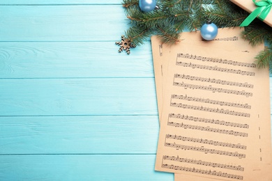 Flat lay composition with Christmas music sheets on light blue wooden background, space for text