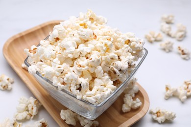 Photo of Bowl of tasty popcorn on white table, closeup