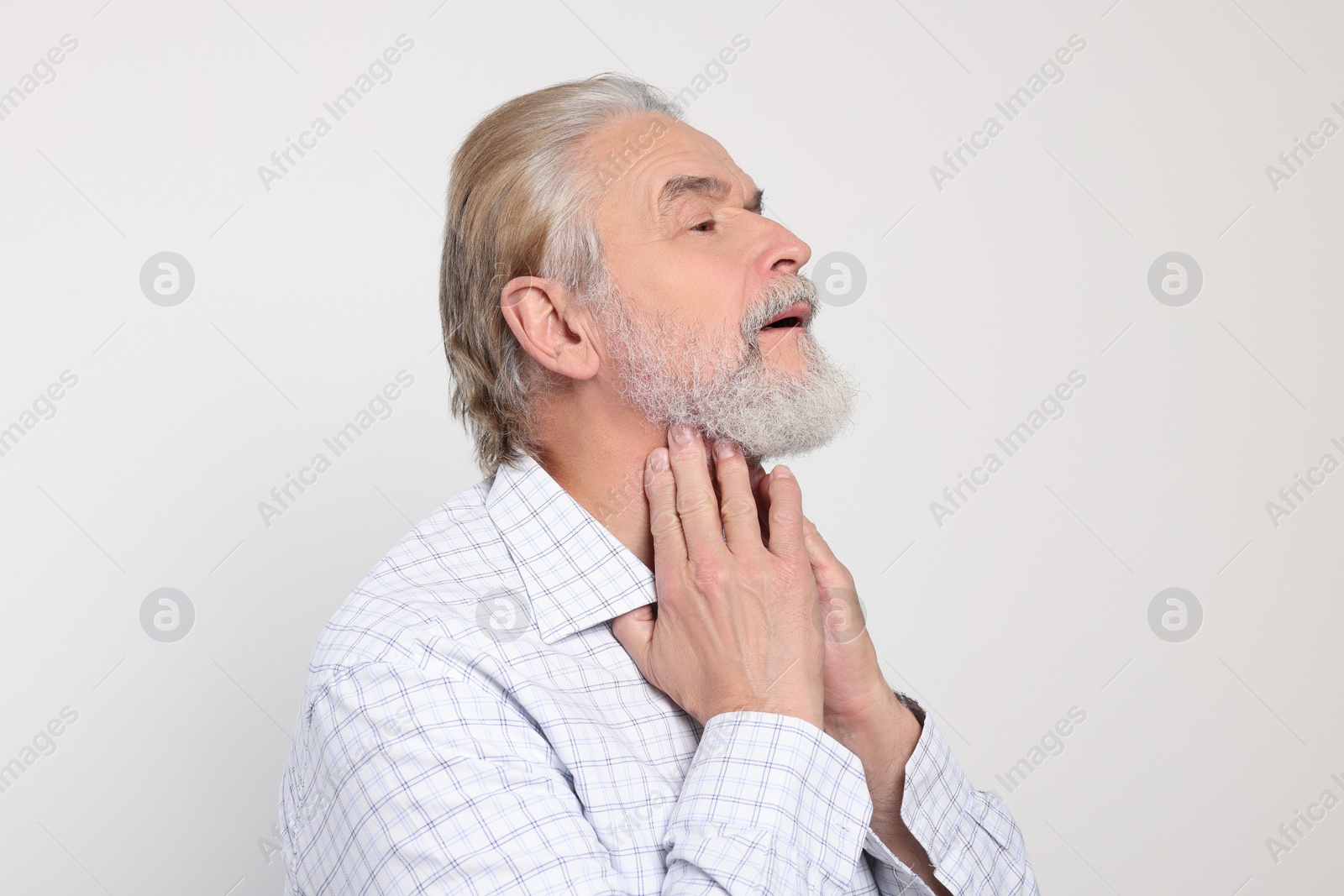 Photo of Senior man suffering from sore throat on white background. Cold symptoms