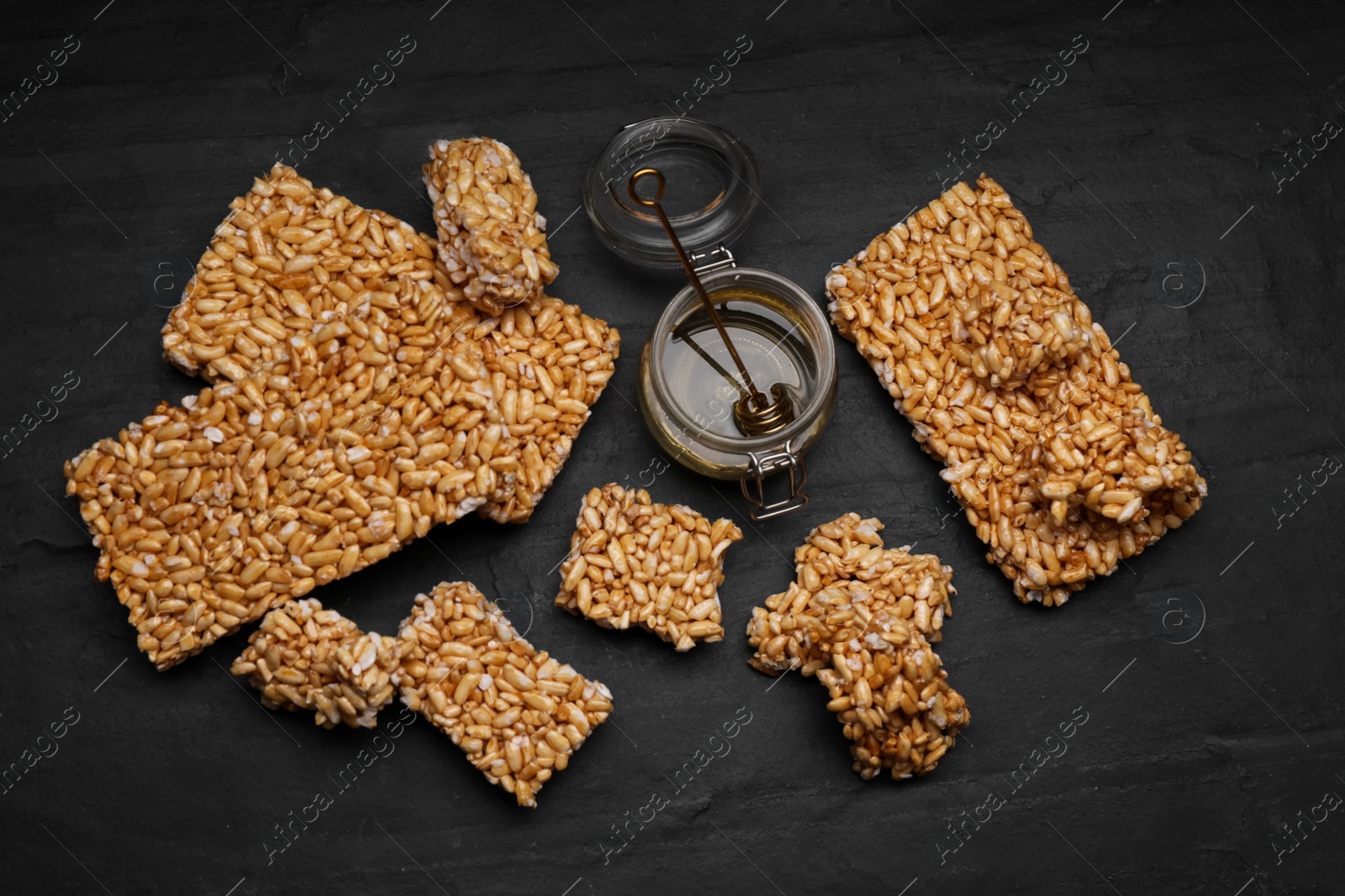 Photo of Puffed rice bars (kozinaki) on black table, flat lay